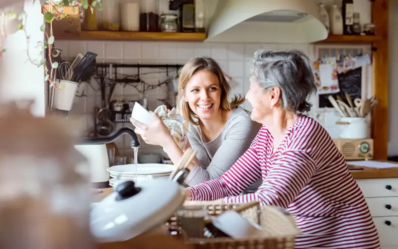 Daughter cooking with elderly parent
