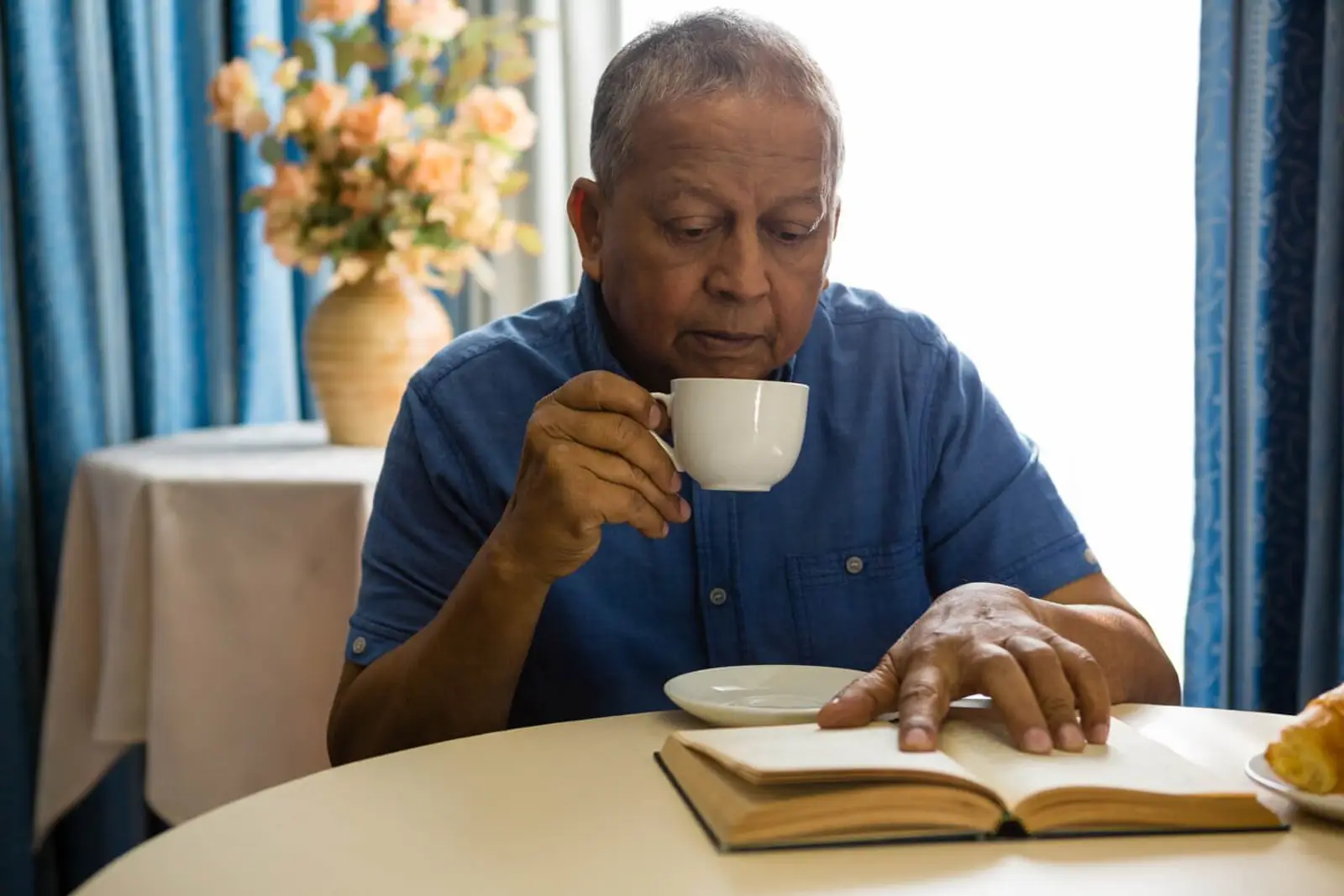 Man reading a book and drinking tea