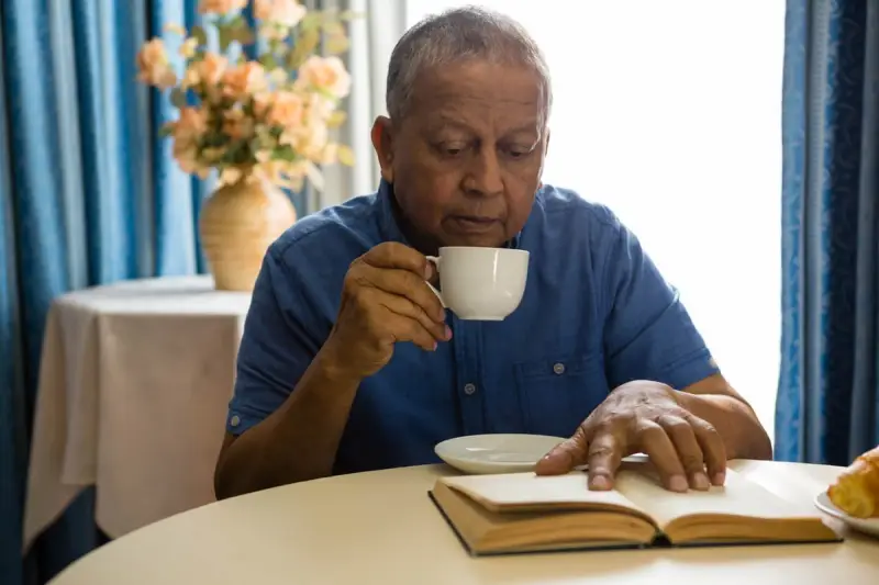 Senior man drinking a cup of tea while reading
