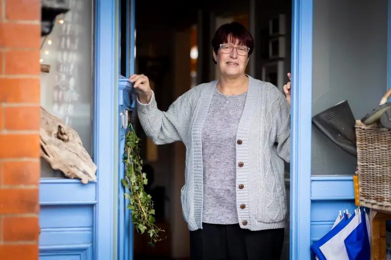 Woman stands in door of her home