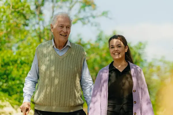 Elderly man taking a walk with carer outside