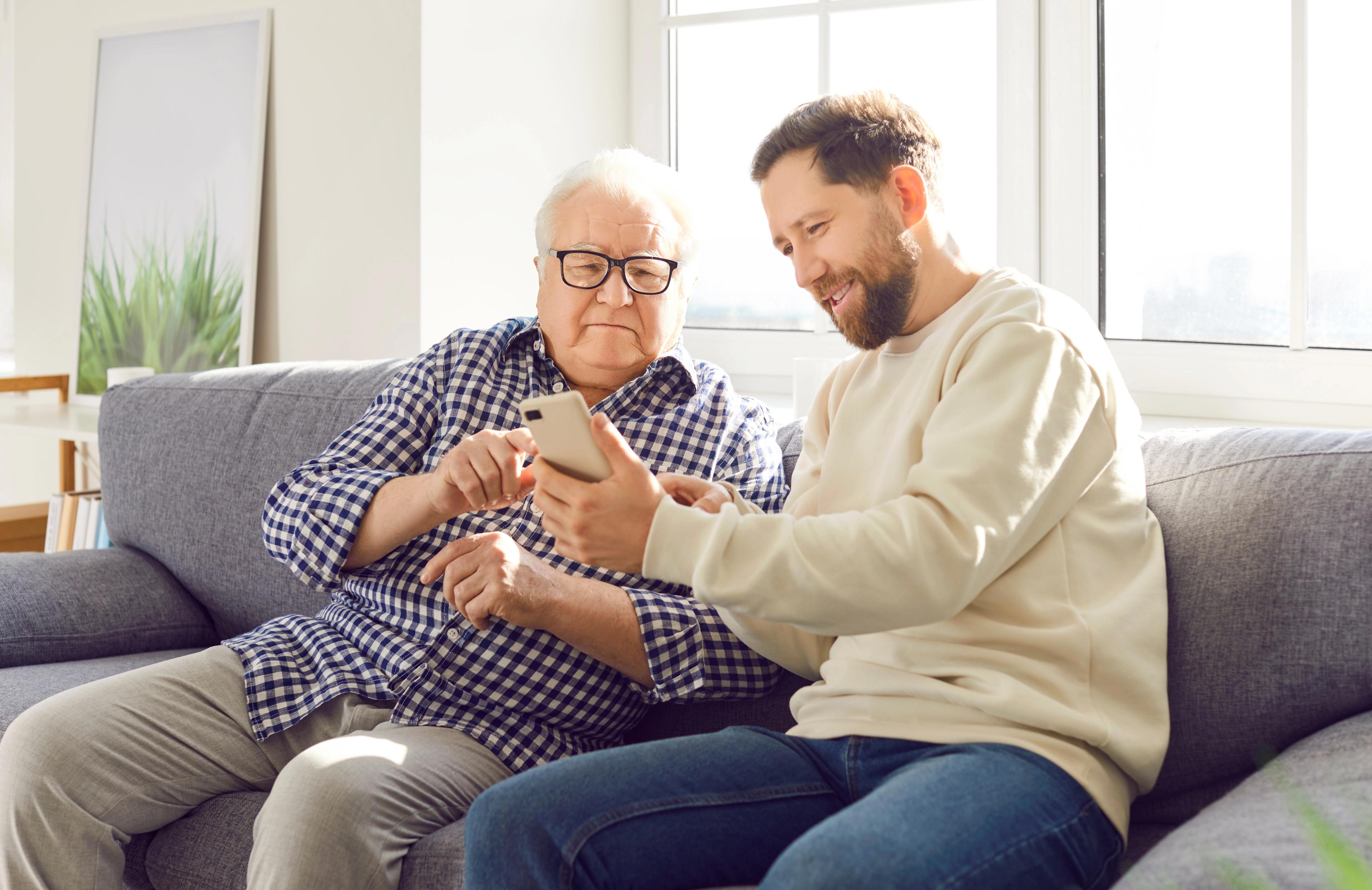 Carer showing something on mobile phone to elderly man