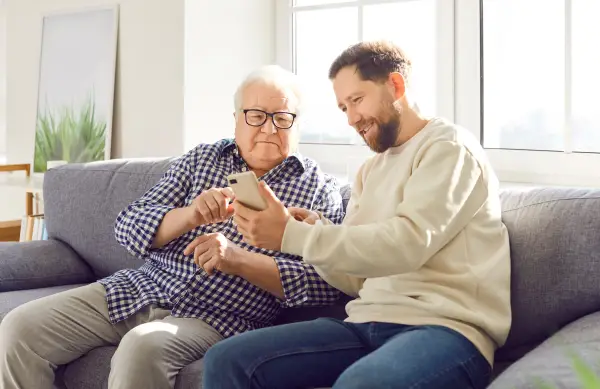 Carer showing something on mobile phone to elderly man