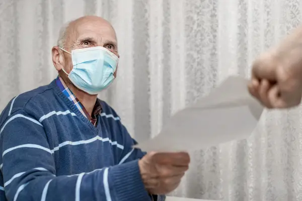 Older man wearing mask and receiving paper