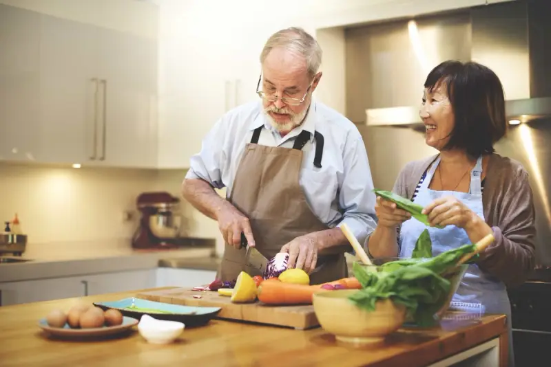 Two people cutting vegetables in the kitchen
