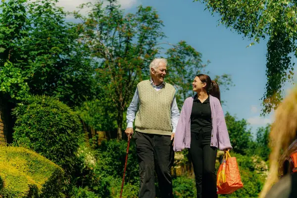 Carer and elderly man walking home from the shop