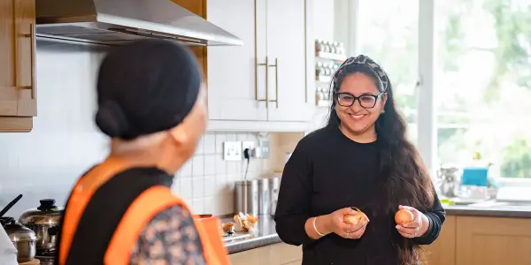 Carer helping old woman in the kitchen
