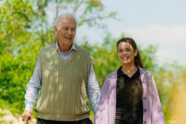 Elderly man walking in the park with his carer