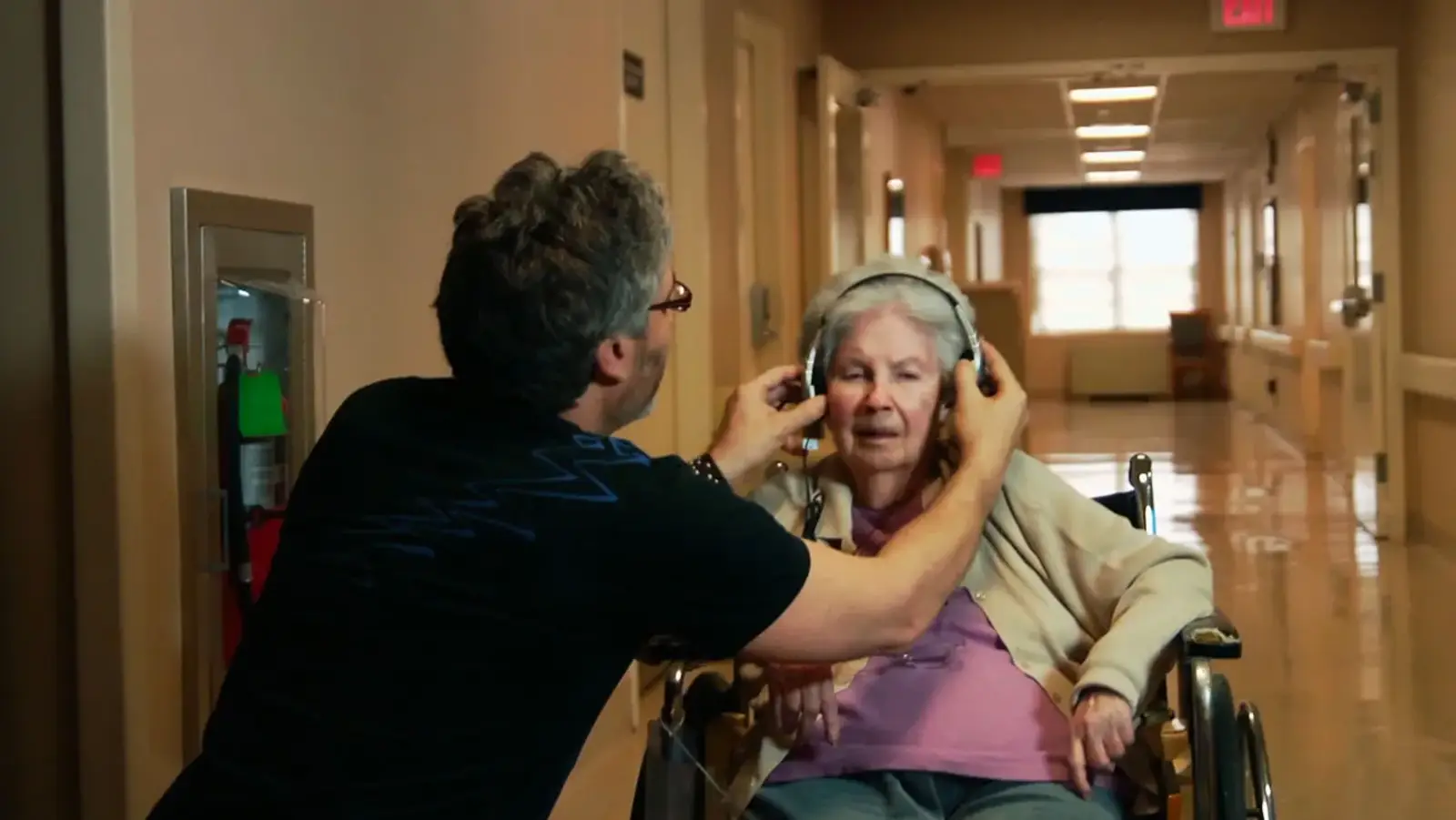 A social worker places headphones on an older woman with dementia to play her favourite music in Alive Inside (2014)