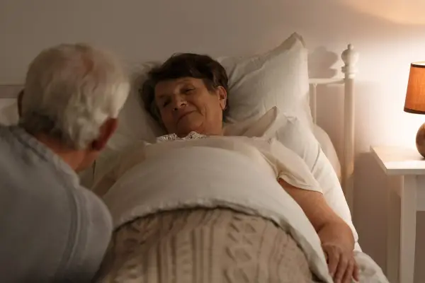 Carer looking over elderly woman sleeping