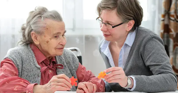 An elderly woman solving puzzles with another woman