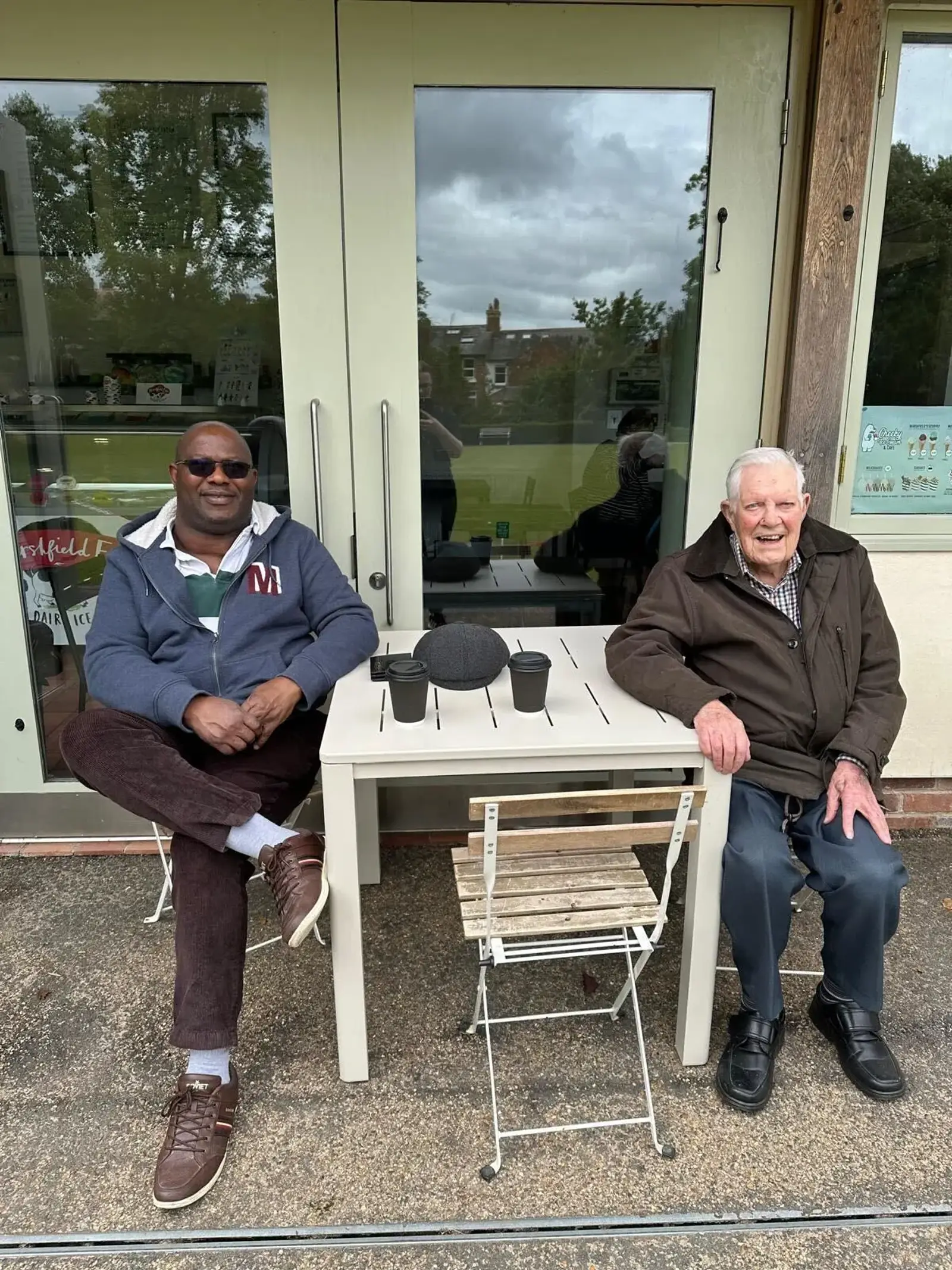 Bob and his carer Godswill having coffee in a coffee shop