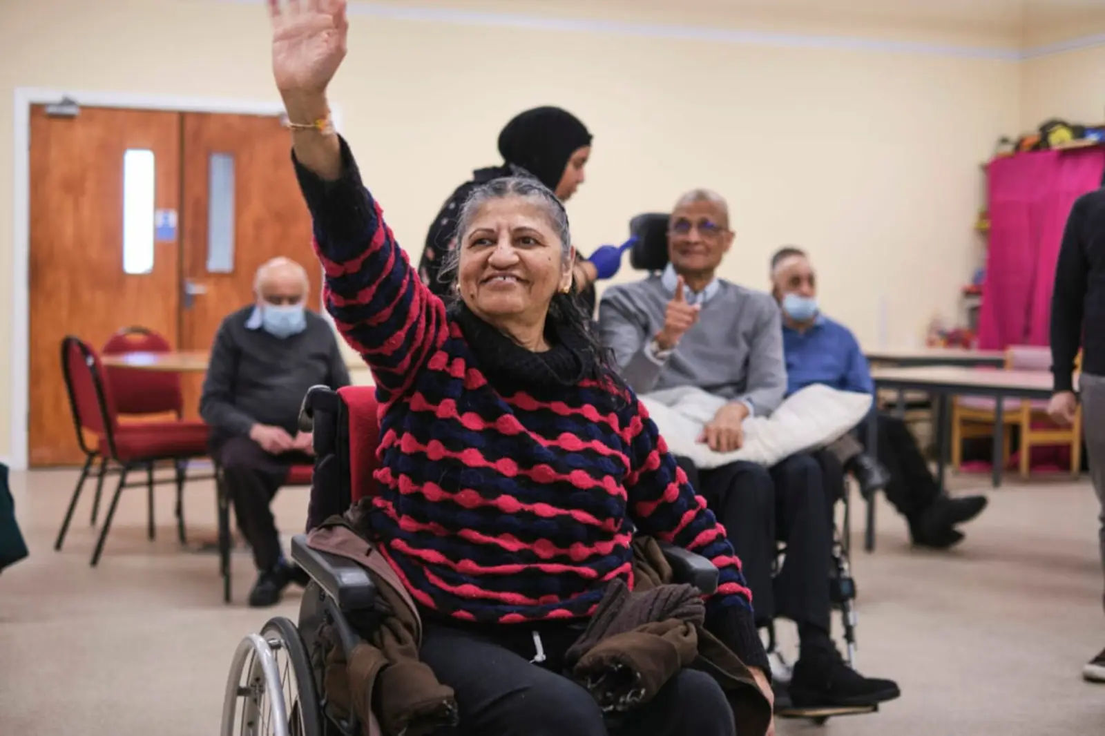 A woman in a wheelchair waving at someone off camera