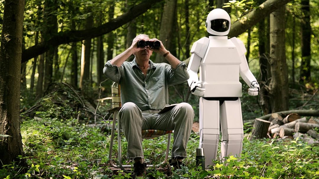 Frank, an older man living with dementia, sits in the woods beside his robot helper in Robot & Frank (2012)