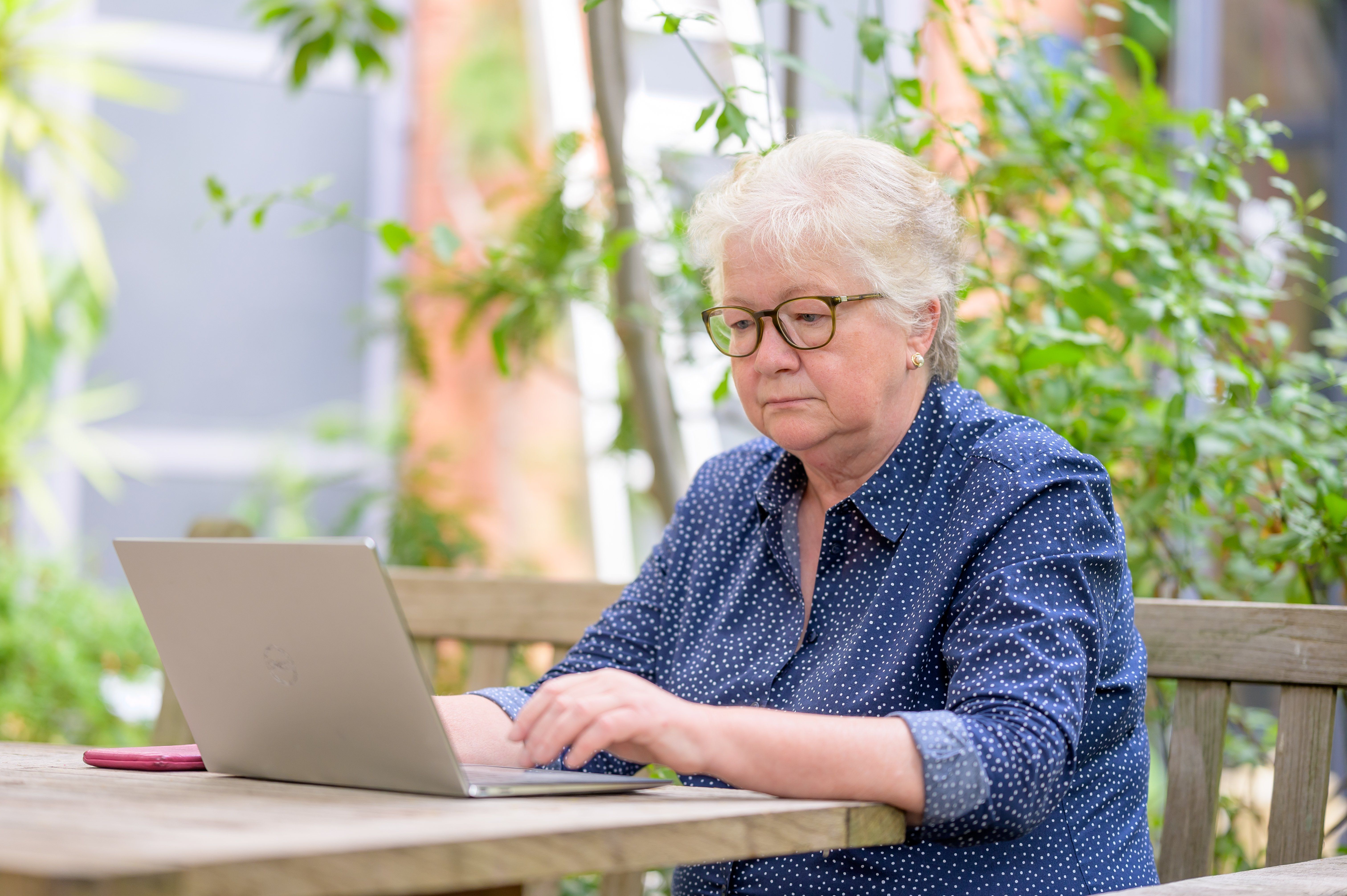 An elderly woman frowing while looking at her laptop