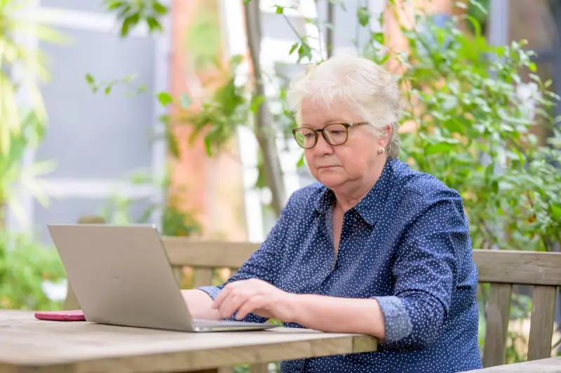 An elderly woman frowing while looking at her laptop