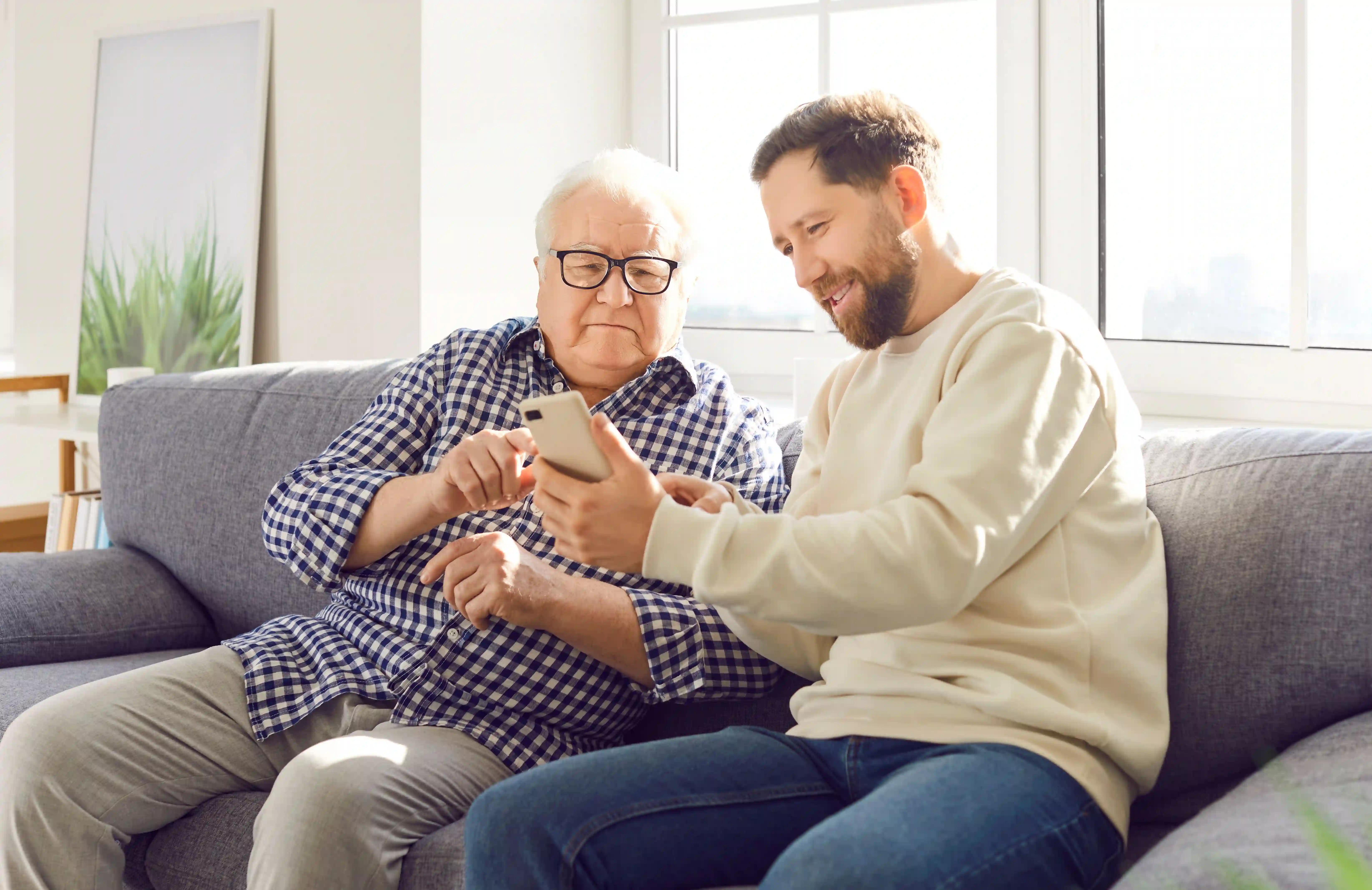 Elderly man and carer looking at a phone