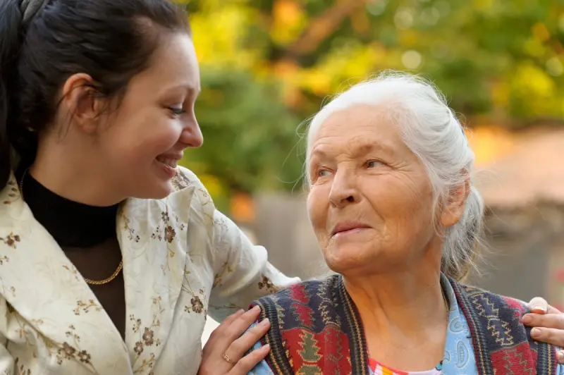 Carer comforting elderly woman