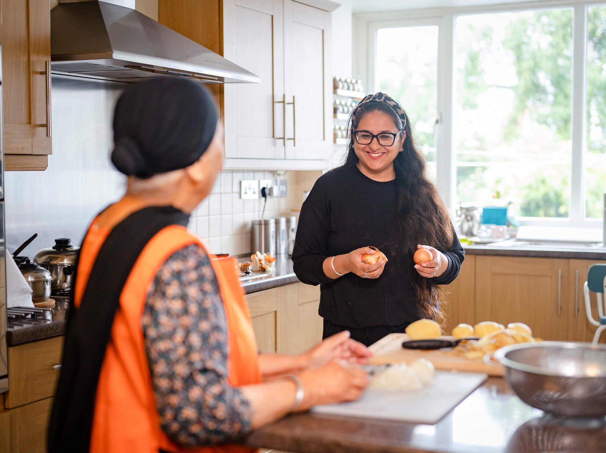 Carer and elderly woman cooking and laughing in the kitchen