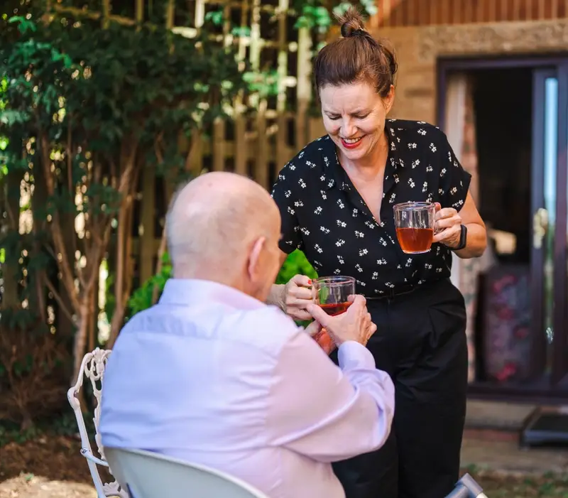 A carer giving tea to an elderly man