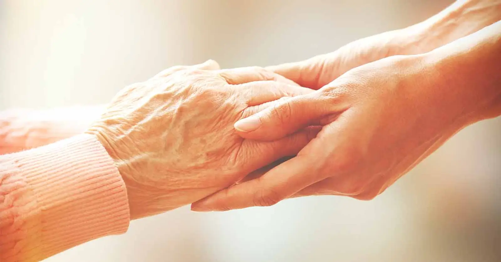 Carer holding elderly woman's hands