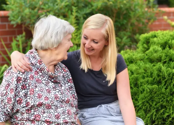 Carer supporting elderly woman outside