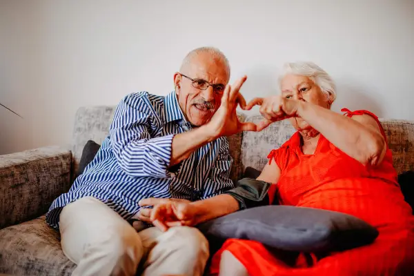Elderly couple making a love heart with their hands