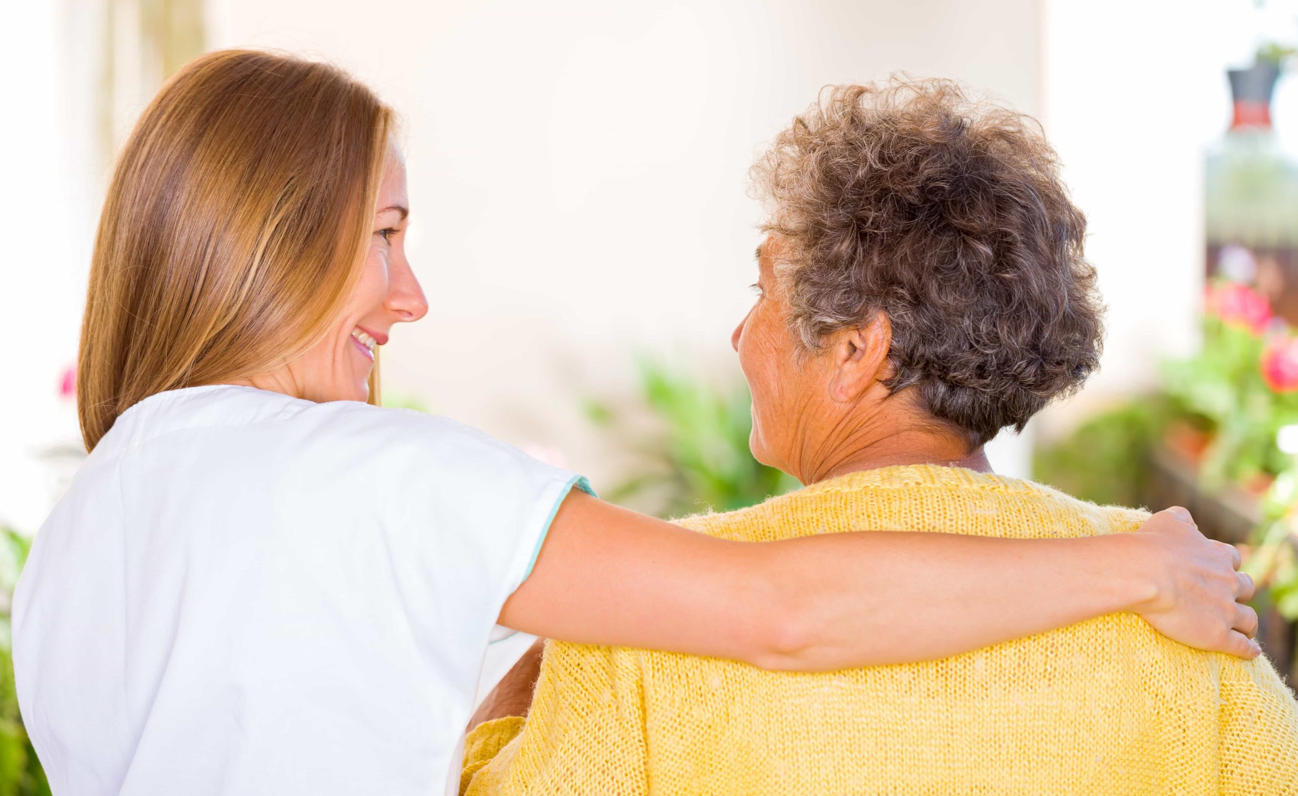 Carer hugging elderly woman
