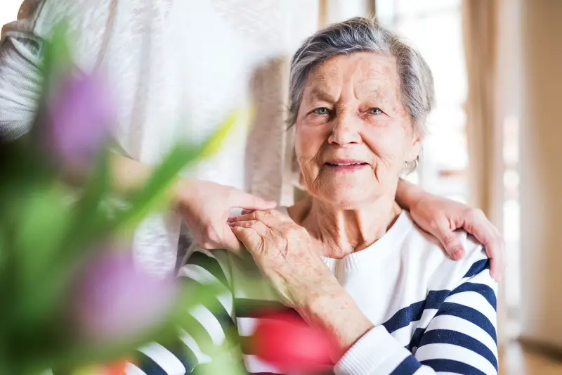 Elderly woman holding her carer's hand