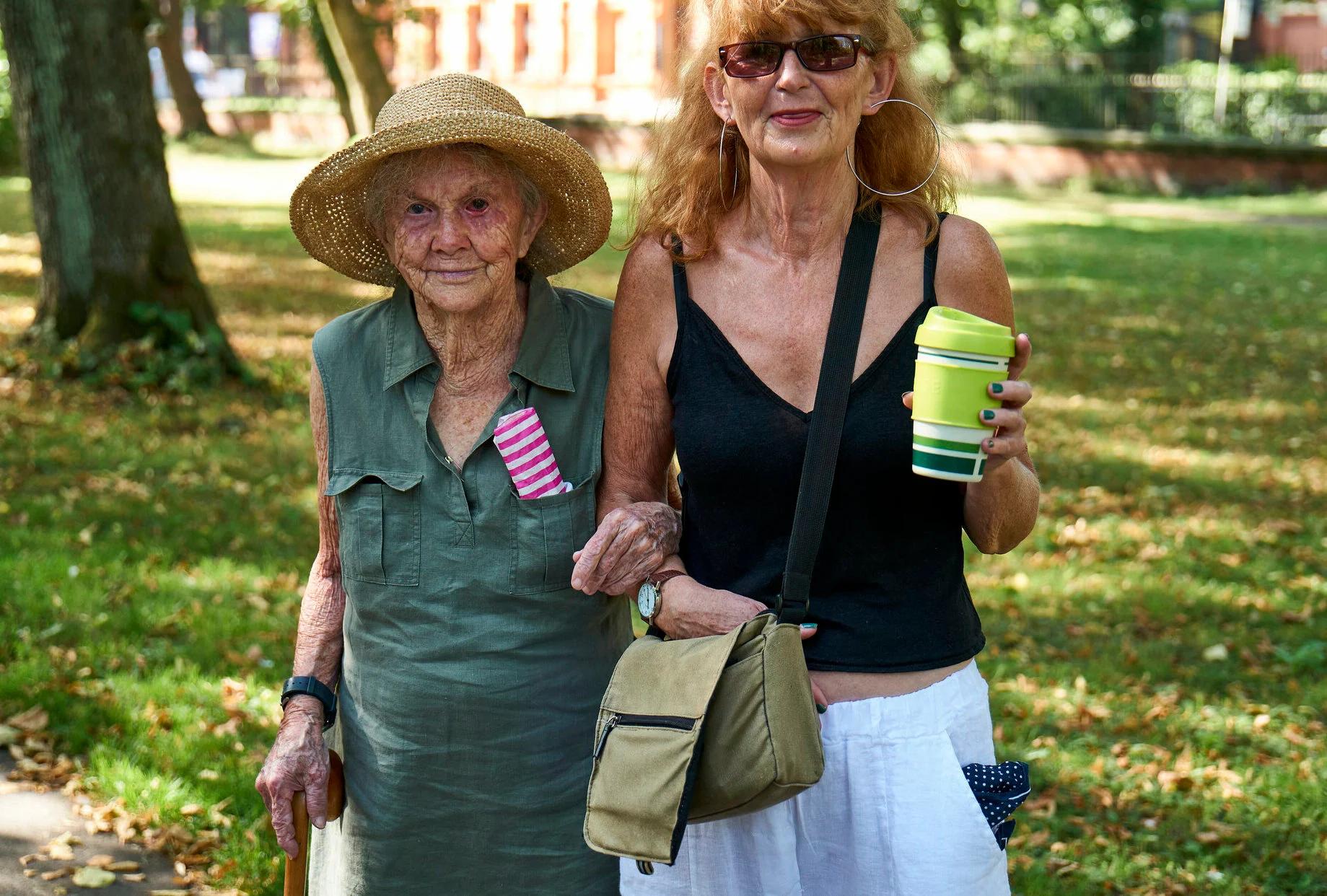 Elderly woman walking in the park with her carer