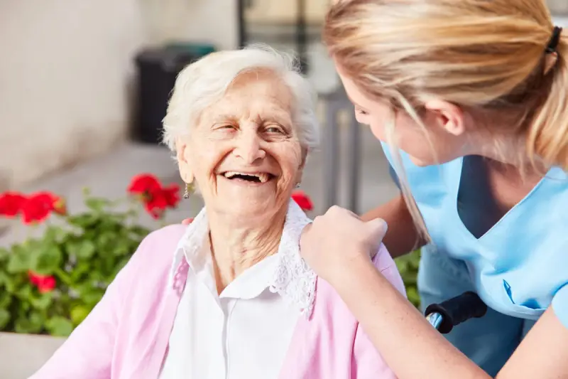 Carer offering support to elderly woman in a wheelchair