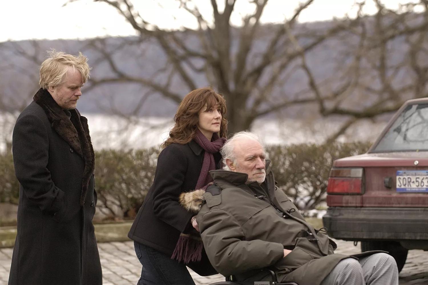 A brother and sister care for their father, who has dementia, as he sits in a wheelchair in The Savages (2007)