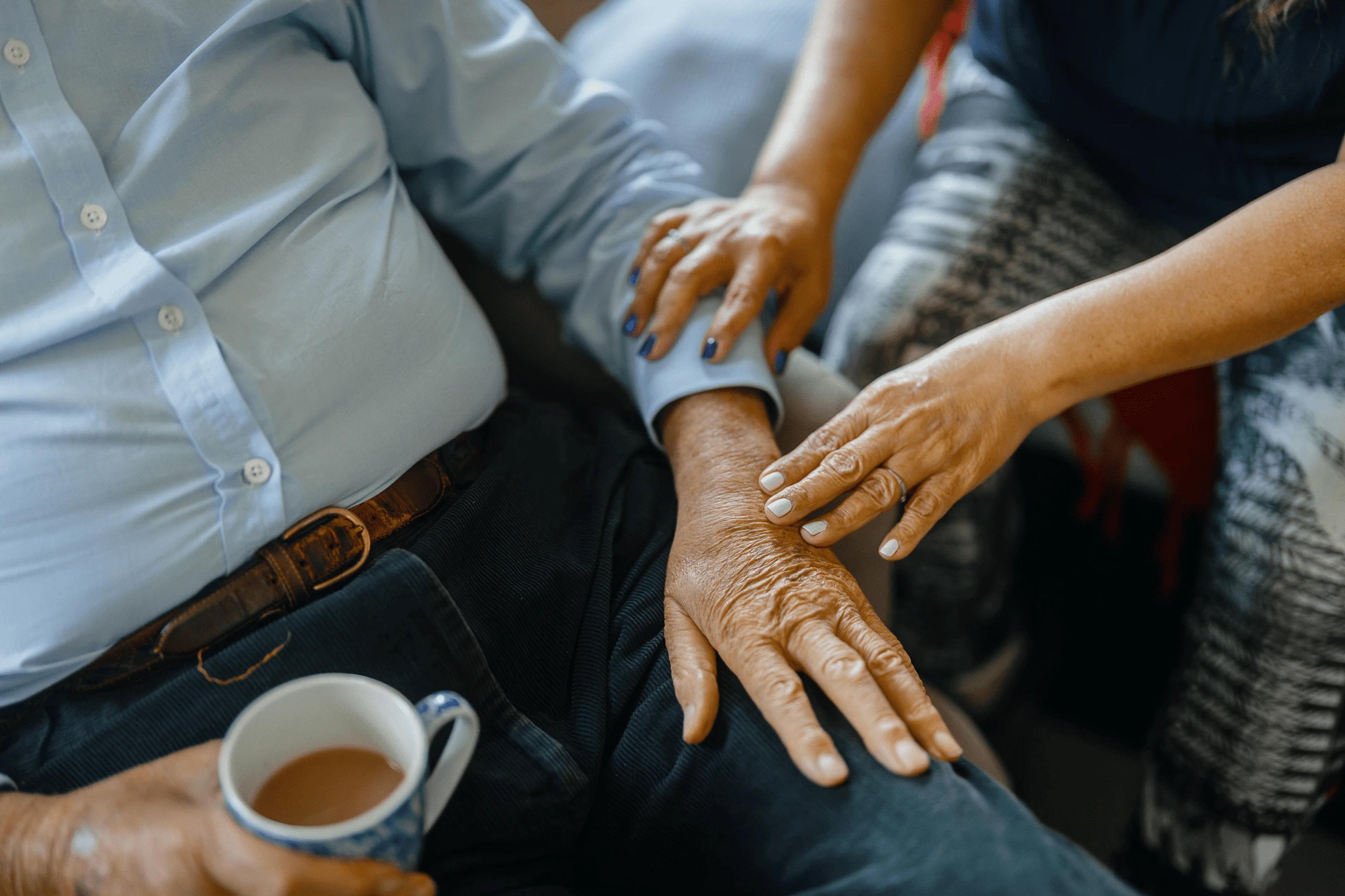 Carer holding elderly man's hand
