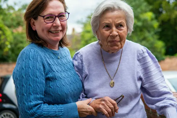 Elderly woman with her carer outside