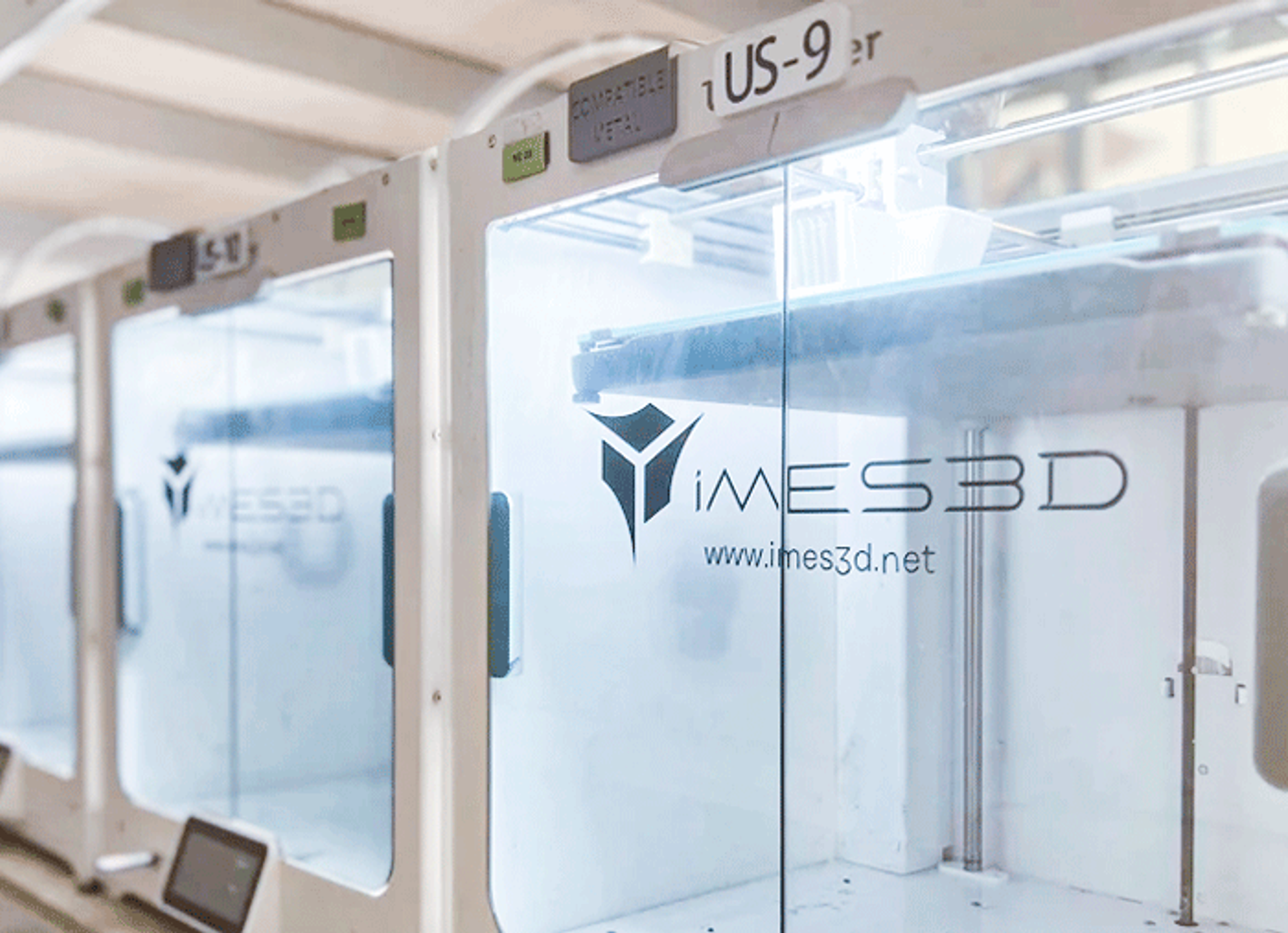A line of 3D printers with a IMES3D logo sticker on each of their doors
