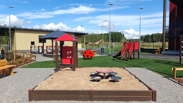 Hiekkalaatikko, taustalla liukumäki ja jousivälineitä.