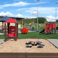 Hiekkalaatikko, taustalla liukumäki ja jousivälineitä.