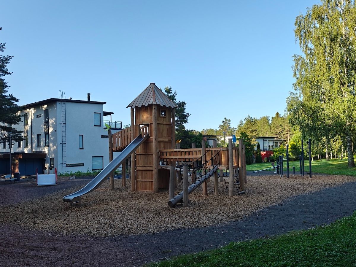 Puinen, linnamainen kiipeilyteline, jossa liukumäki. 