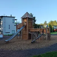 Puinen, linnamainen kiipeilyteline, jossa liukumäki.