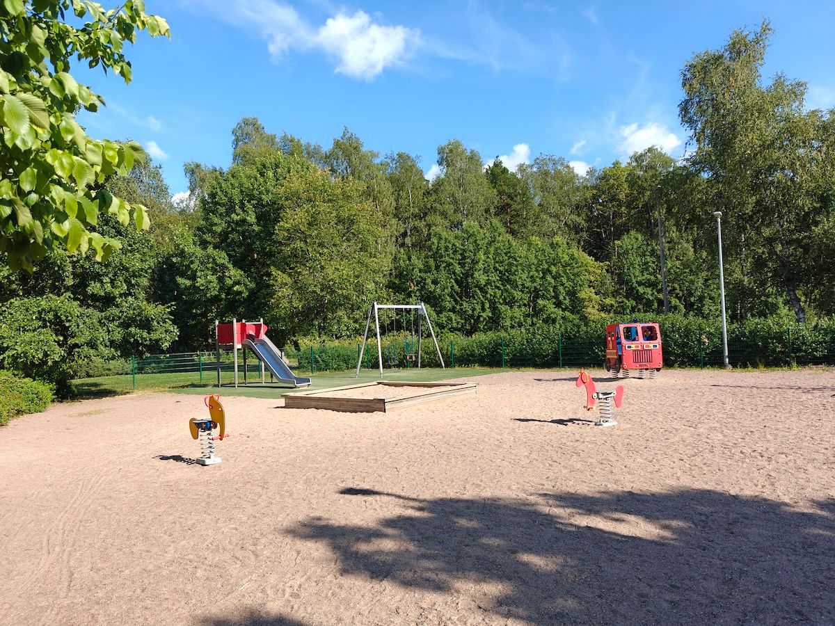 Liukumäki, keinut, paloautoteline, jousivälineitä ja hiekkalaatikko.