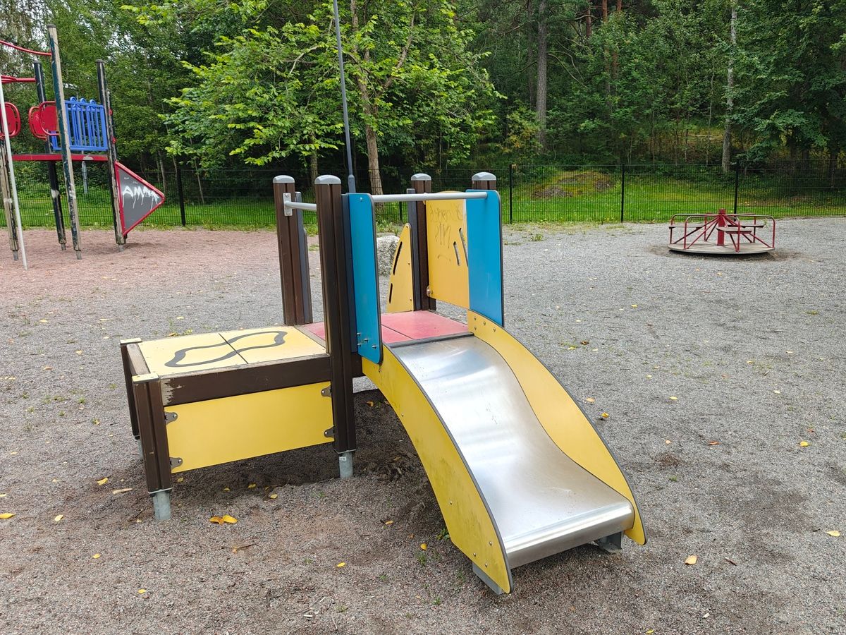 Pienemmille sopiva liukumäki, taustalla karuselli.