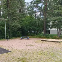 Kaksi jousivälinettä, hiekkalaatikko ja karuselli.