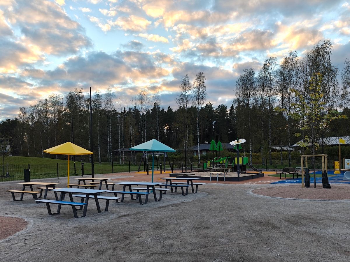 Penkkejä, aurinkosuojia, iso hiekkalaatikko, kiipeilyteline pienemmille lapsille sekä vauvakeinu välilaudalla.
