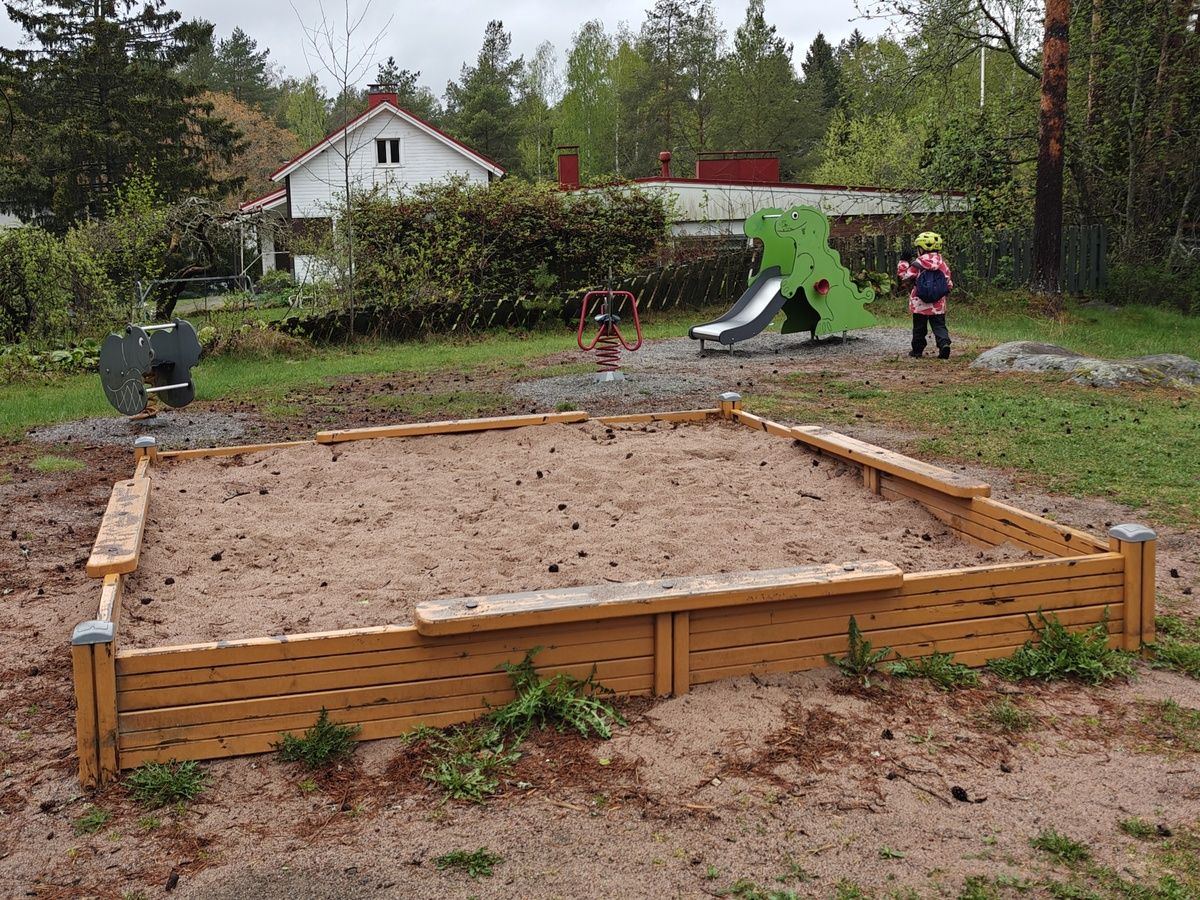 Hiekkalaatikko, jousivälineitä ja pieni liukumäki.