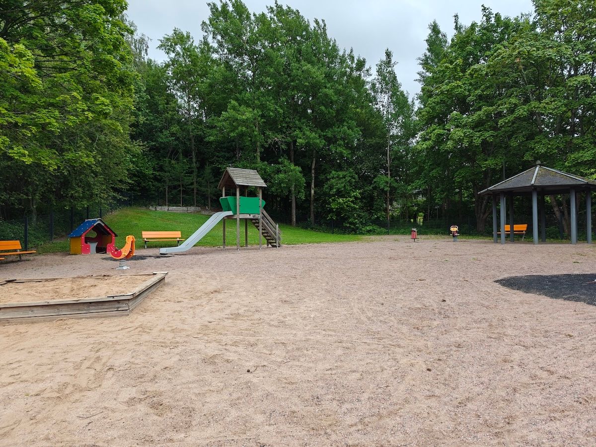 Liukumäki, muutama jousiväline, hiekkalaatikko, penkkejä ja katos.