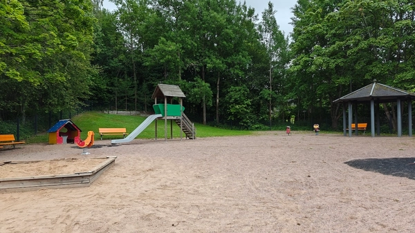 Liukumäki, muutama jousiväline, hiekkalaatikko, penkkejä ja katos.