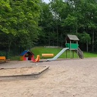 Liukumäki, muutama jousiväline, hiekkalaatikko, penkkejä ja katos.