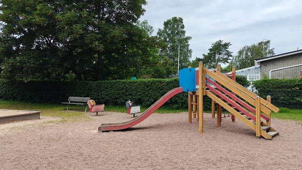 Liukumäki, kaksi jousivälinettä ja hiekkalaatikon kulma.