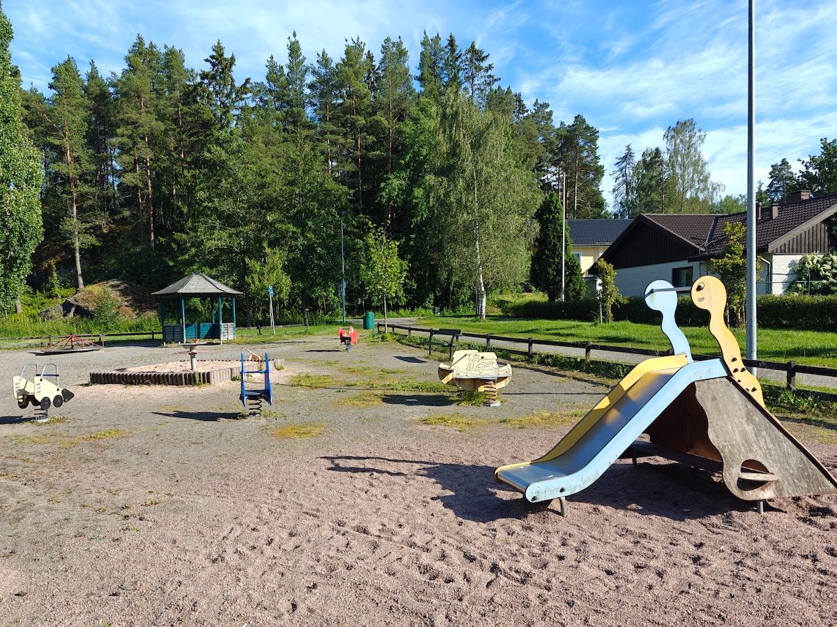 Pieni liukumäki, jousivälineitä ja hiekkalaatikko.