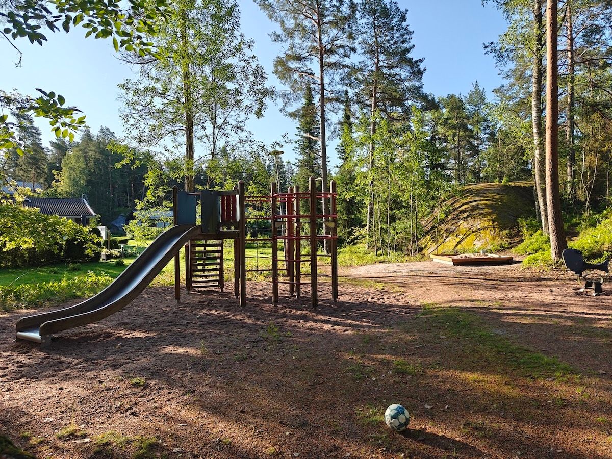 Kiipeilyteline, jossa liukumäki ja hiekkalaatikko.